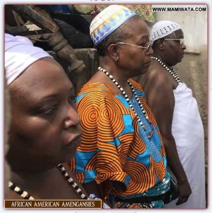 Mama Zogbe, center, with Shrine Mother Mama Apokassi on right (closer to front of screen) and Mama Zodede on Left, wearing all white. 